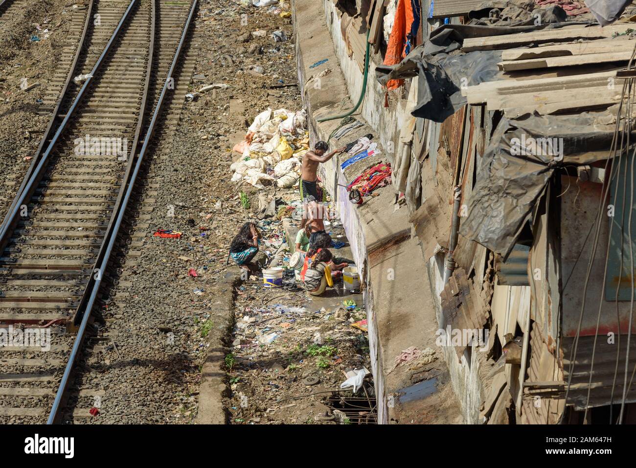 Indische Leute waschen auf der Straße in der Nähe der Suburban-Eisenbahn in Dharavi Slum in Mumbai. Indien Stockfoto