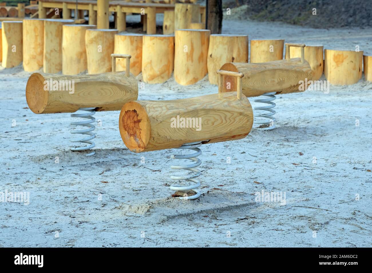Schaukeln auf einer Federausrüstung für Spielplätze im Freien. Baumstämme auf Metallfedern am Sand im Park. Spielplatz aus Holz Stockfoto