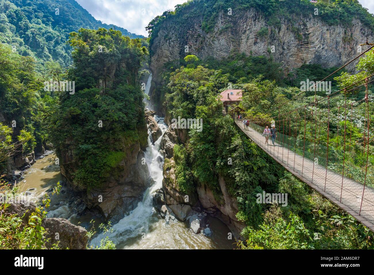 Wasserfall El Pailón del Diablo und Brücke mit Touristen am Fluss Pastaza bei Baños in Ecuador. Stockfoto