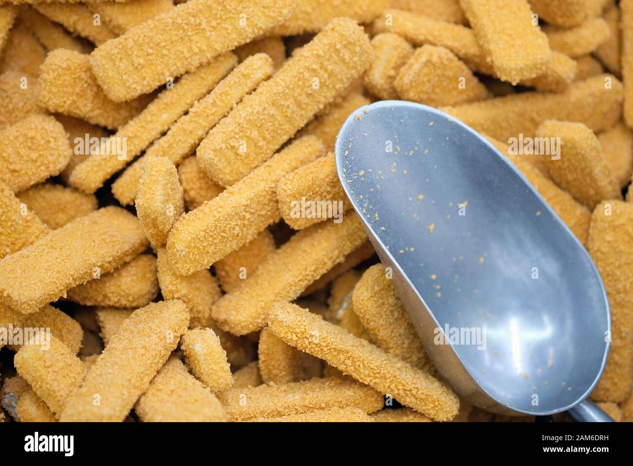 Nahaufnahme von Fischfingern gefürchtet und Metallschaufel. Fisch- und Fleischhalbwaren im Laden. Fast Food. Stockfoto