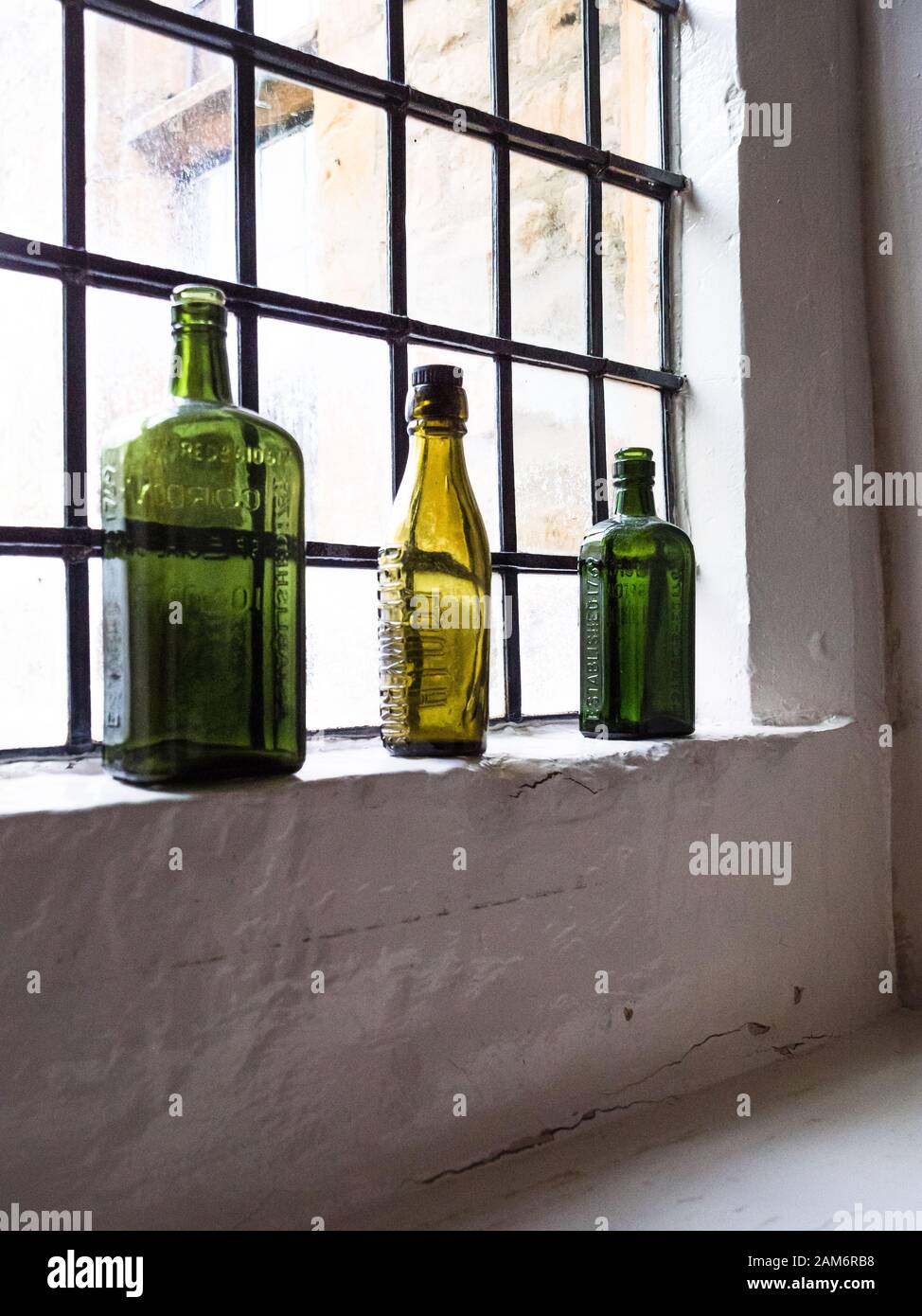 Bunte leere Gin-Flaschen und ein altmodischer Wasserkocher an einem Fenstervorsprung in einem alten englischen "Coaching inn" in Den Cotswolds. Stockfoto
