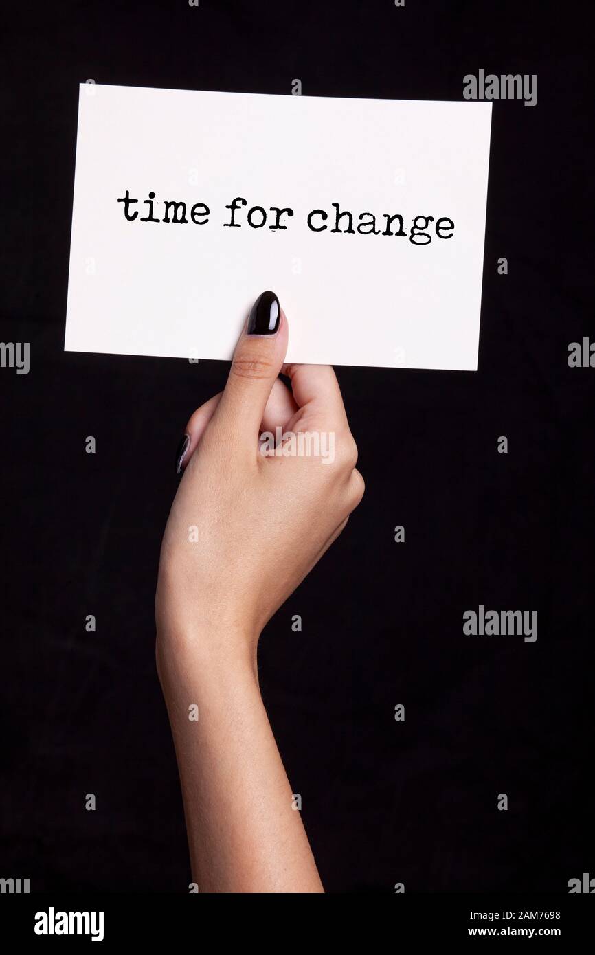 Hand, die eine weiße Karte auf schwarzem Hintergrund - Zeit für Veränderung Stockfoto