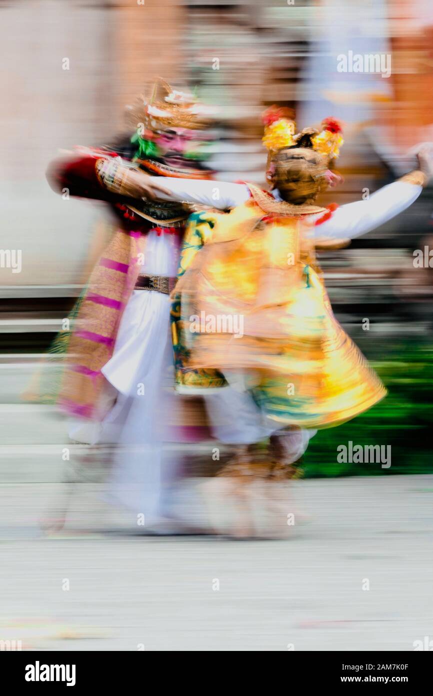 Wirbelnde Bewegung von männlichen und weiblichen hinduistischen Tempeltänzern, die in gelben, goldenen, roten und weißen Kostümen und goldenen Kronen gekleidet sind, die im Tempelhof tanzen. Stockfoto