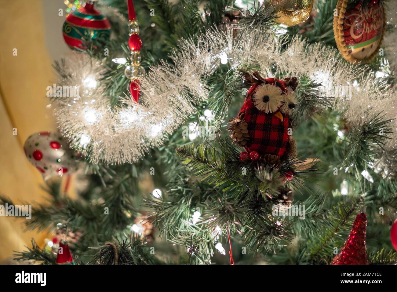 Nahaufnahme von einer beleuchteten Weihnachtsbaum mit Eule Ornament, Weihnachtsbeleuchtung und Bälle. Stockfoto