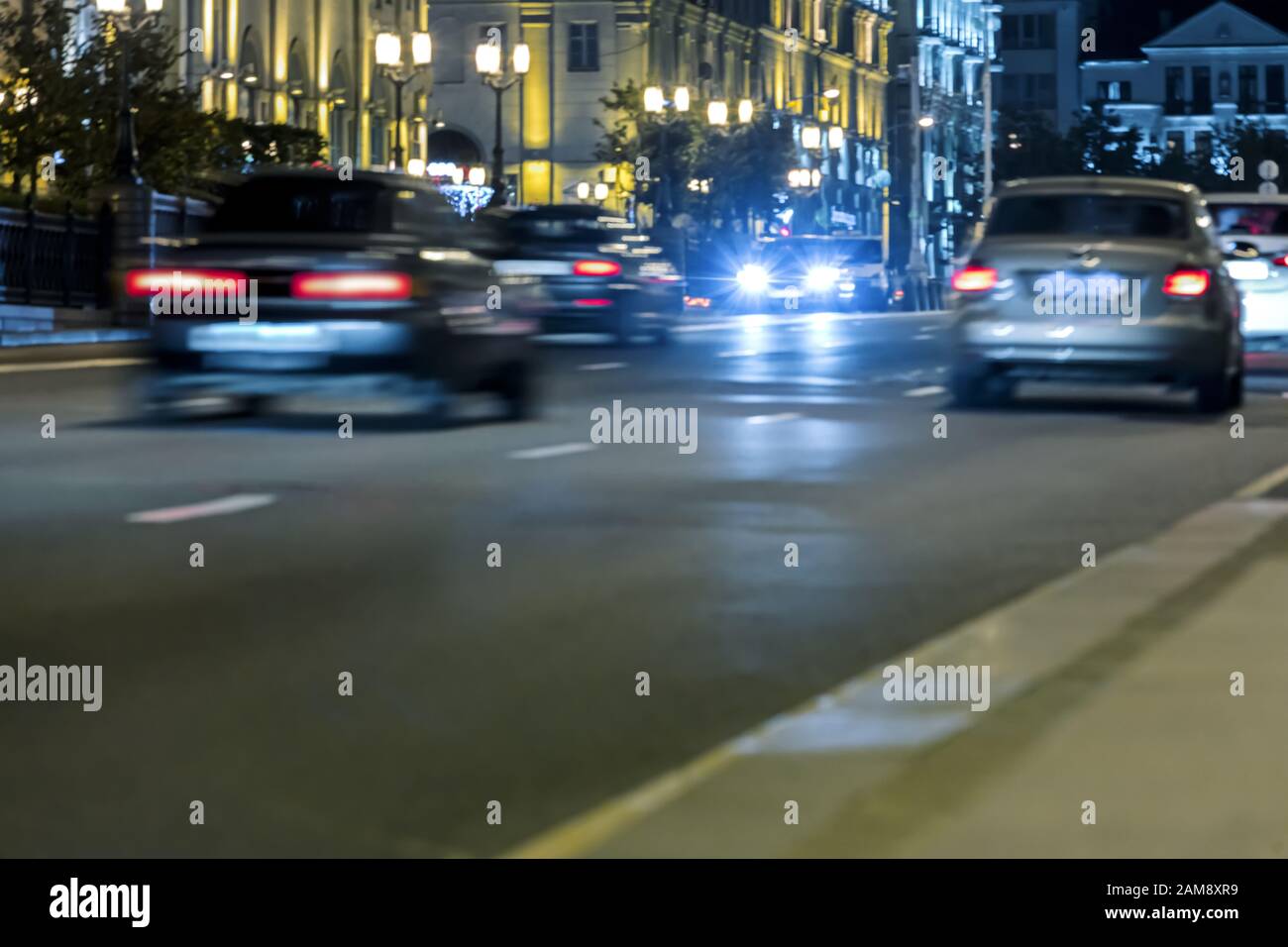 Unscharfe Sicht auf den Autoverkehr, der in der nächtlichen Stadtstraße mit unscharfen Lichtern fährt Stockfoto