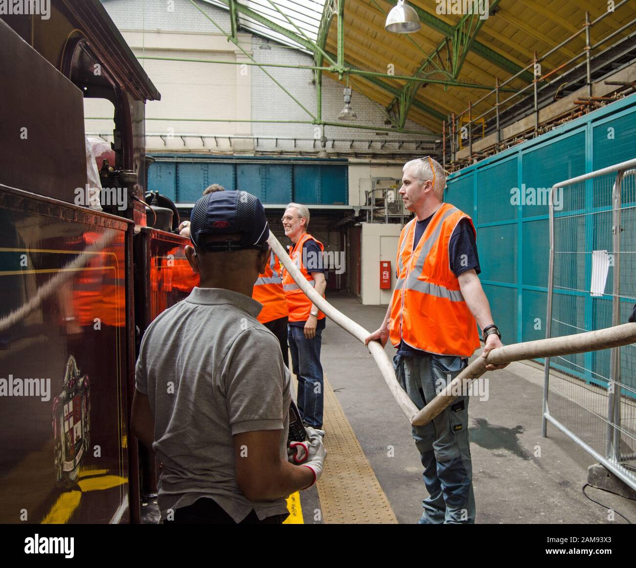 London, Großbritannien - 22. Juni 2019: Eisenbahnarbeiter, die das Wasser in der letzten Dampfmaschine toppen, die auf der District Line zur Ealing Broadway Station fährt Stockfoto
