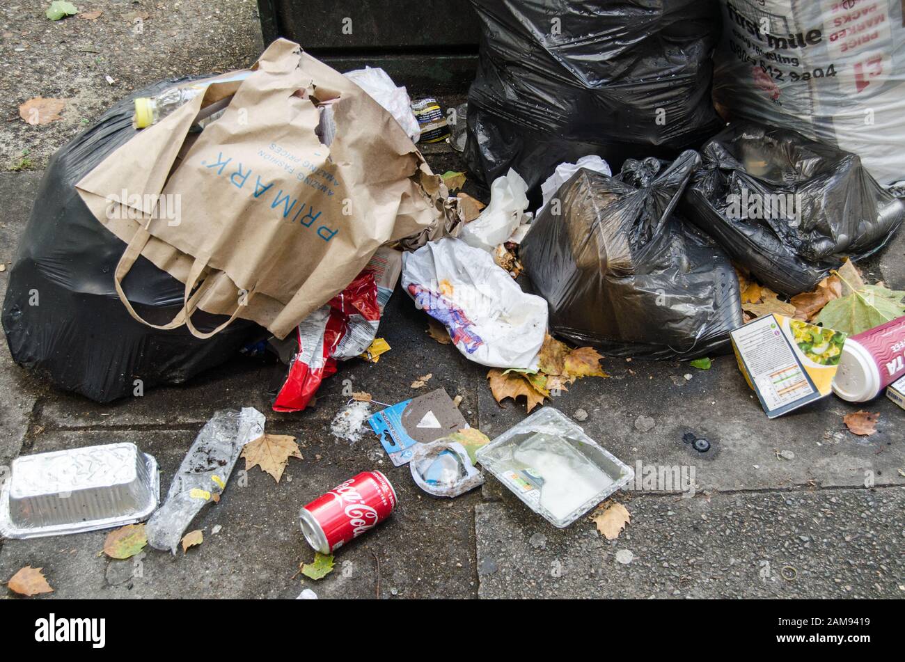 London, Großbritannien - 20. Juli 2019: Müllhaufen, einschließlich Zigarettenpackungen und Lebensmittelabfälle, die auf einem Straßenbelag in Southwark, South London, zurückgelassen wurden. Stockfoto
