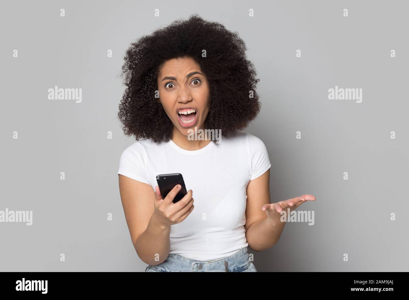 Wütende afroamerikanische Frau irritiert durch kaputtes Gerät, niedrige Batterie. Stockfoto