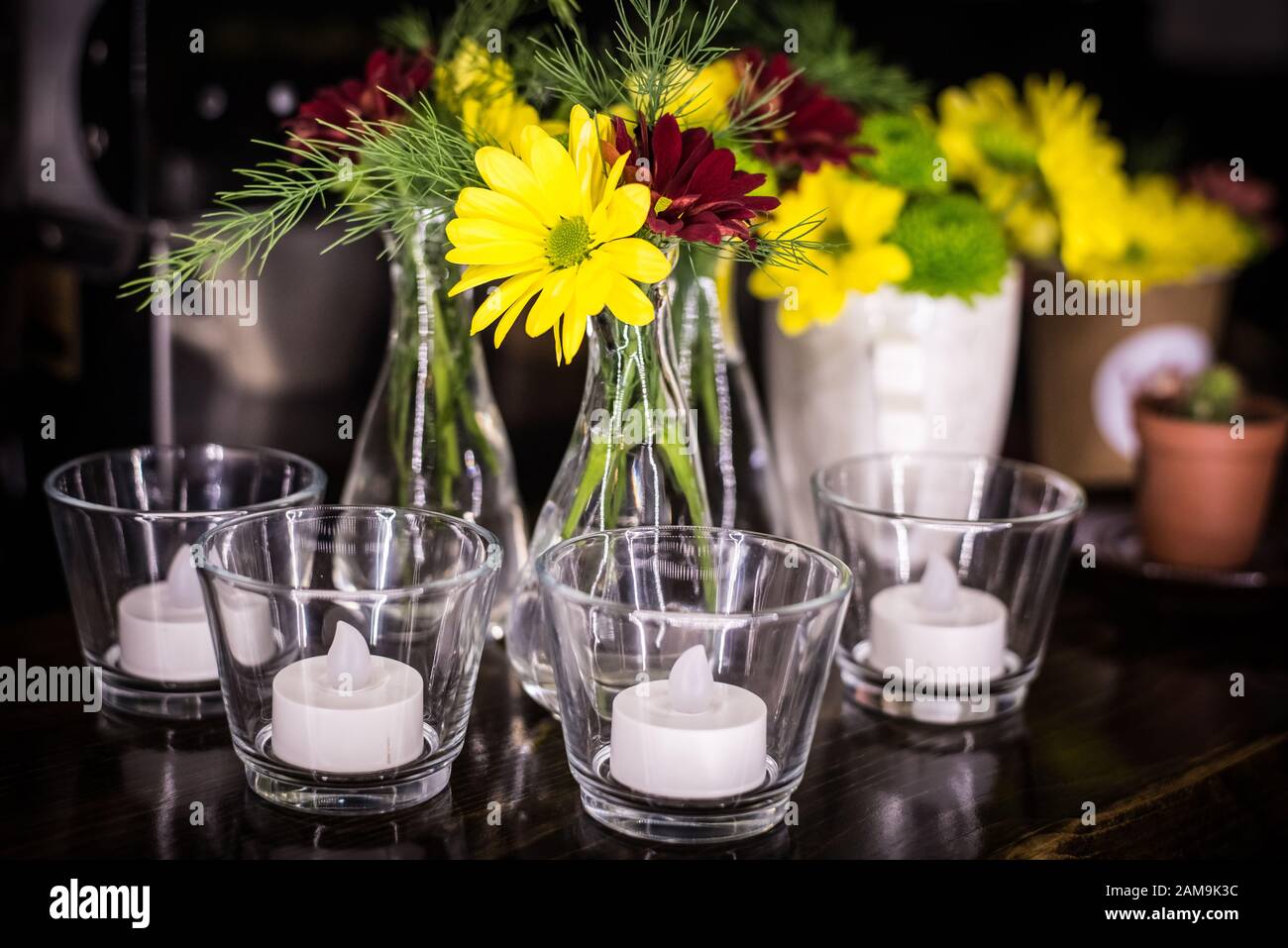 Kerzen in einem Glas und frische Blumen in einem dunklen Raum. Stockfoto