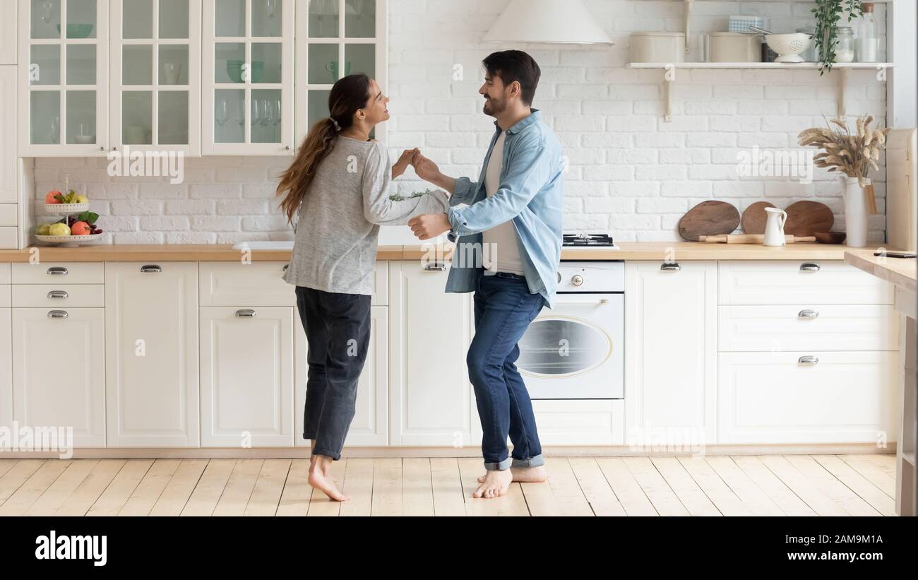 Glückliches Familienpaar tanzt barfuß auf Holzboden in der Küche  Stockfotografie - Alamy