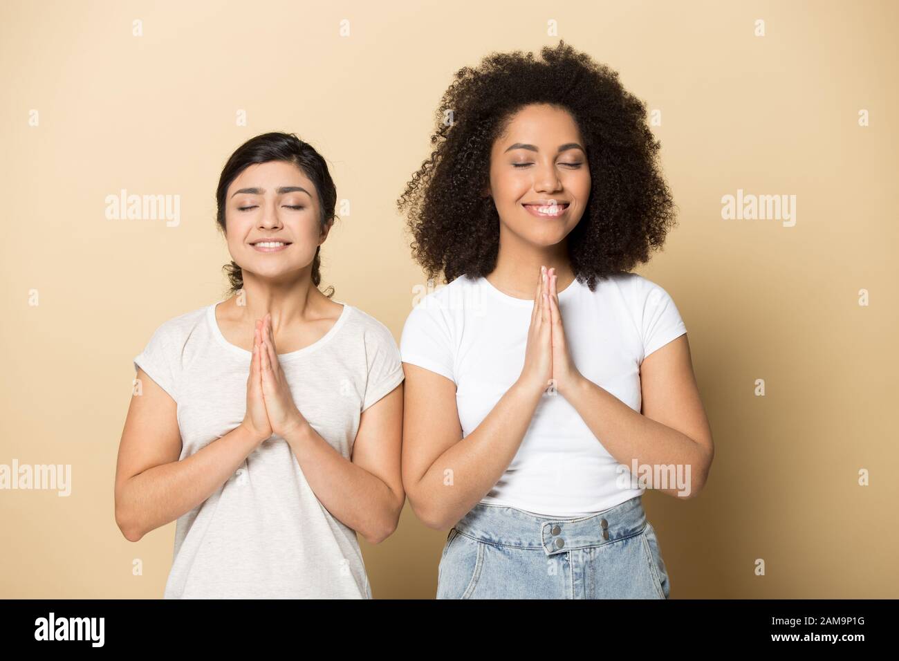 Treue multikulturelle weibliche Freunde, die für viel Glück beten. Stockfoto