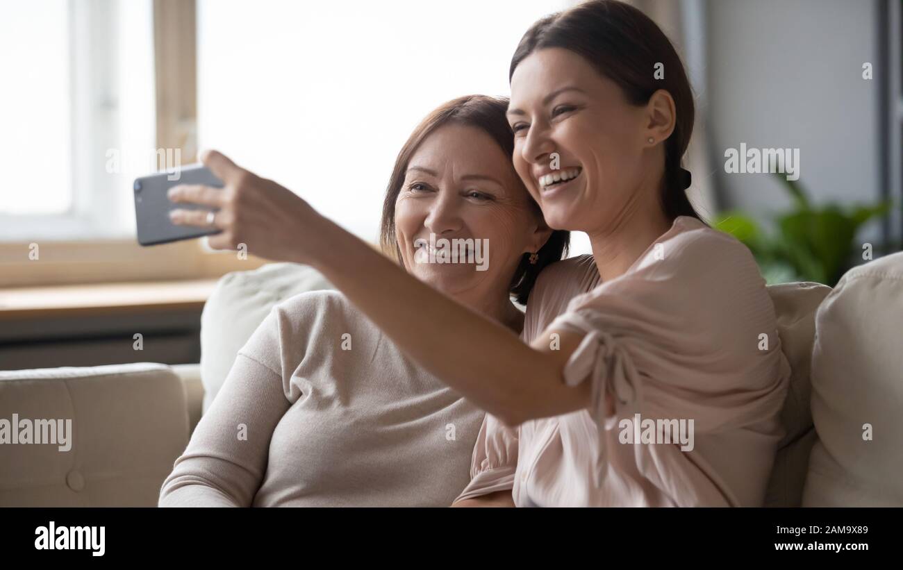 Lächelnde Erwachsene Mutter und Tochter posieren für selfie auf Zelle Stockfoto