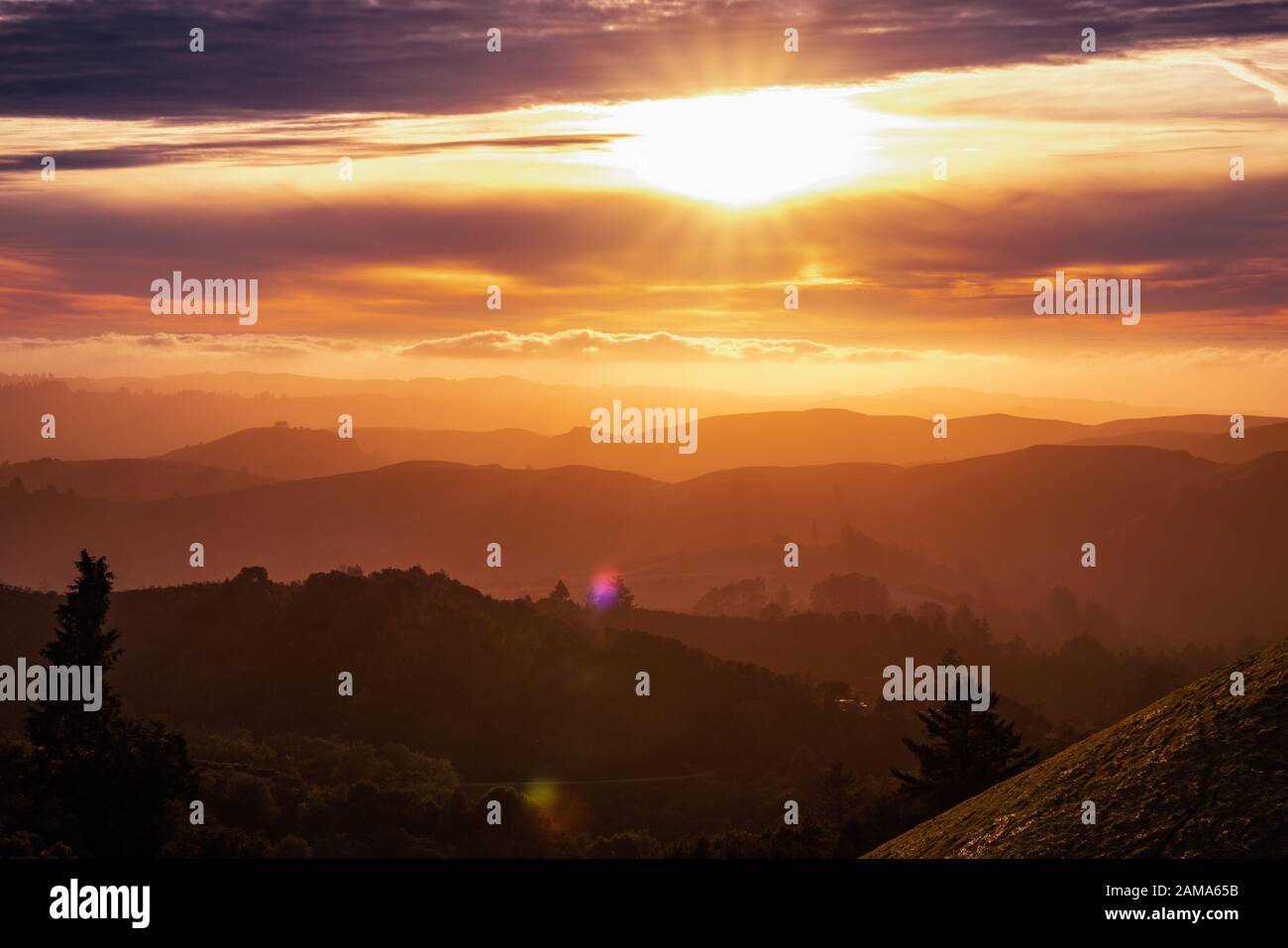 Sonnenlicht platzt durch die Wolken und beleuchtet die Hügel und Täler der Santa Cruz Berge, Wolken über dem Himmel und dem Pazifischen Ozean; Sa Stockfoto