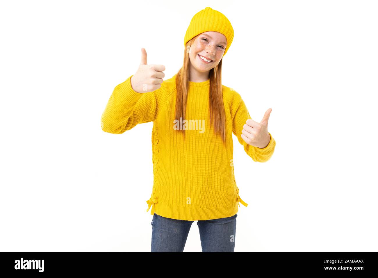 Fröhliches Teenager-Mädchen mit roten Haaren, gelbem Hoodie und Hose zeigt wie isoliert auf weißem Hintergrund. Stockfoto
