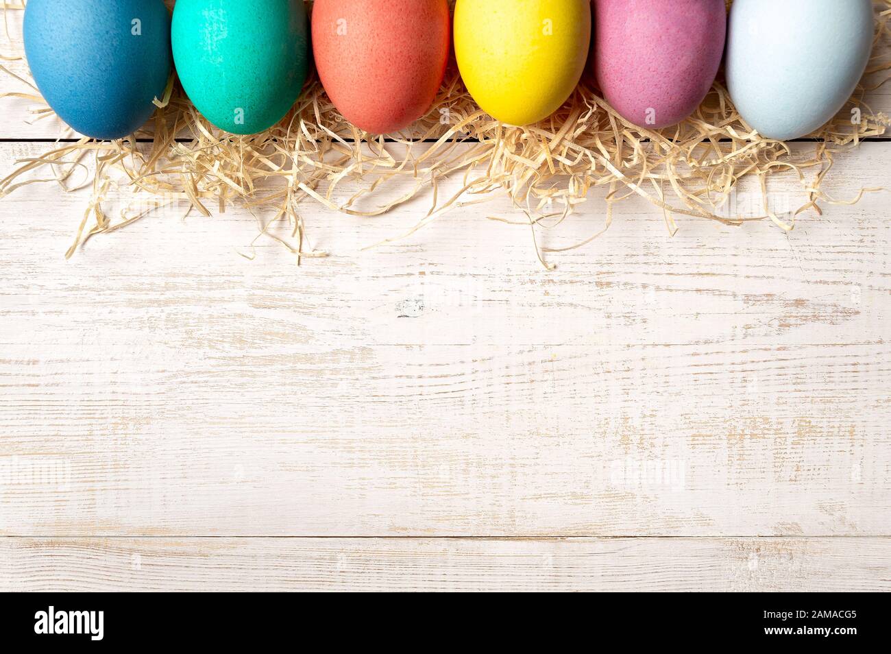 Osterkonzept. Bunte Eier auf weißem Holzhintergrund mit Platz für Text. Draufsicht oder flache Lage Stockfoto