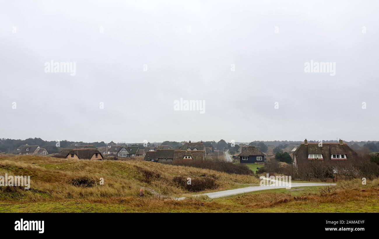 Auf einer Düne stehend, mit Blick auf eine Gruppe traditioneller Ferienhäuser in der Nähe von Buren auf der Wattenmeerinsel Ameland. Stockfoto