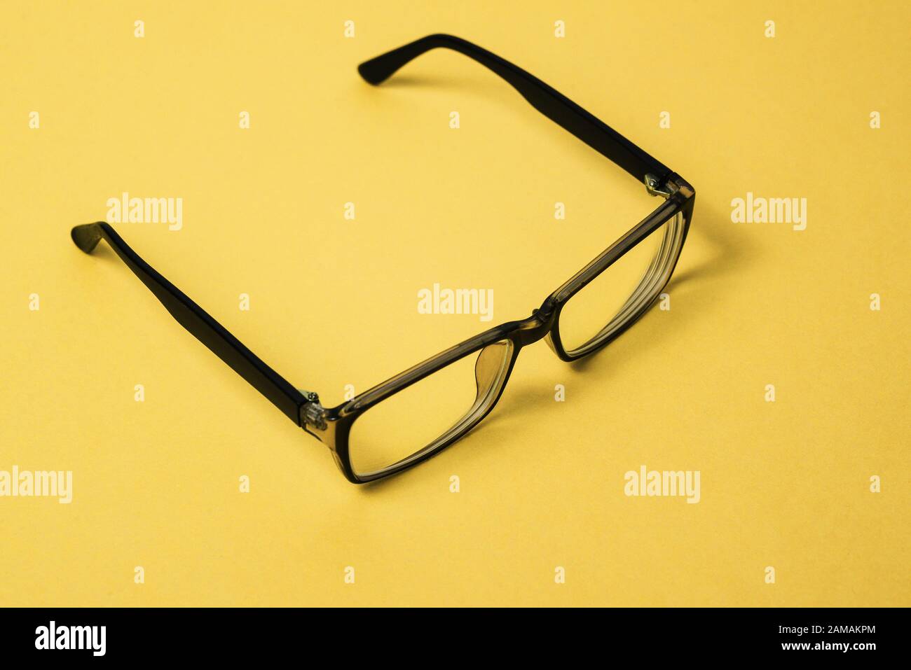 Schwarze Brille mit klaren Linsen. Brillenrahmen auf gelbem Hintergrund. Brille zur Korrektur menschlicher Visionen oder zur Arbeit an einem Computer. Augenschutz Stockfoto