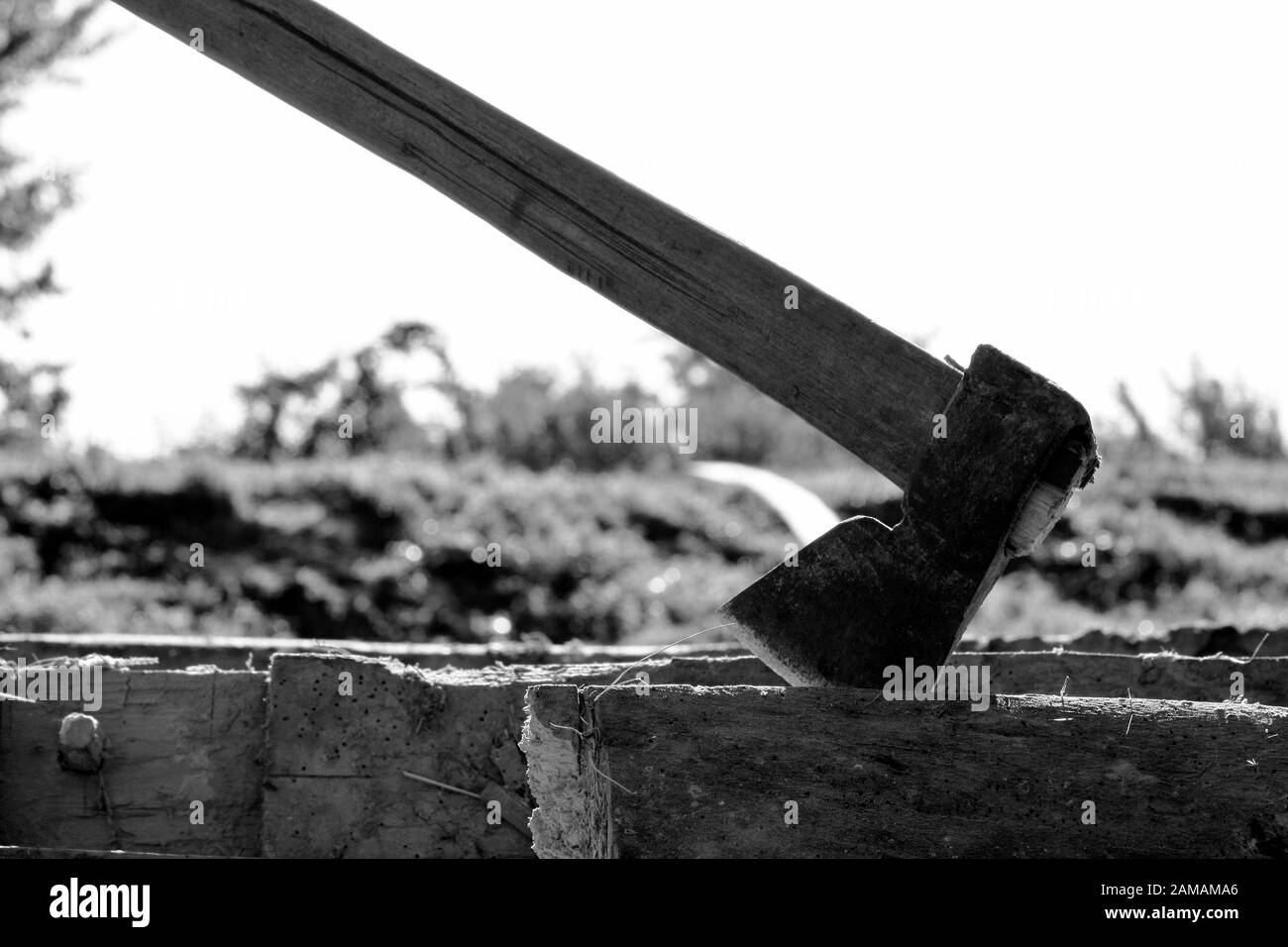 Schwarz-Weiß-Foto einer Axt in einem alten Balken. Detail des Holzschneidegeräts . Stockfoto