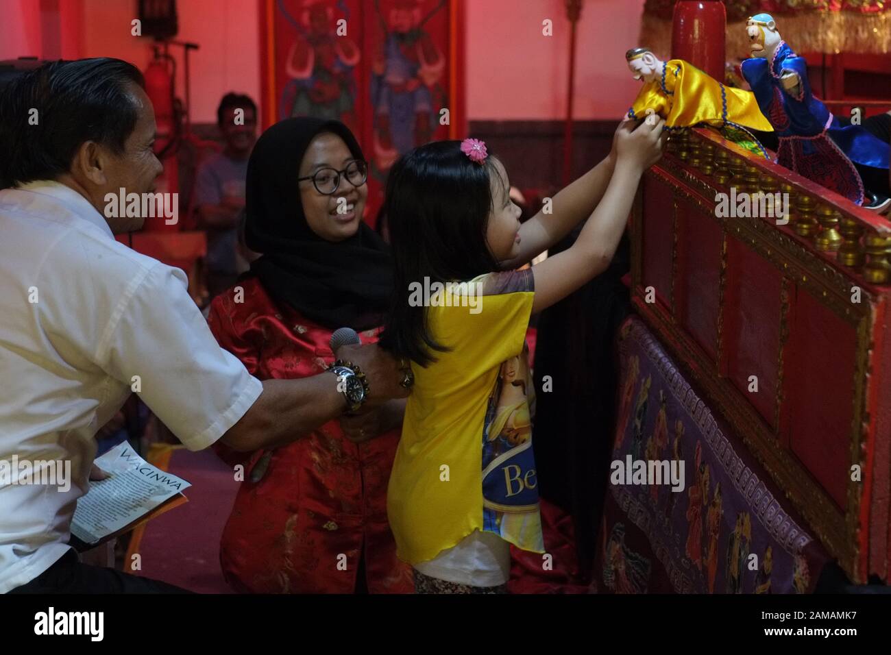 Ein Vater, seine Tochter und eine muslimische Frau vor einer traditionellen chinesischen Puppenschau. Stockfoto