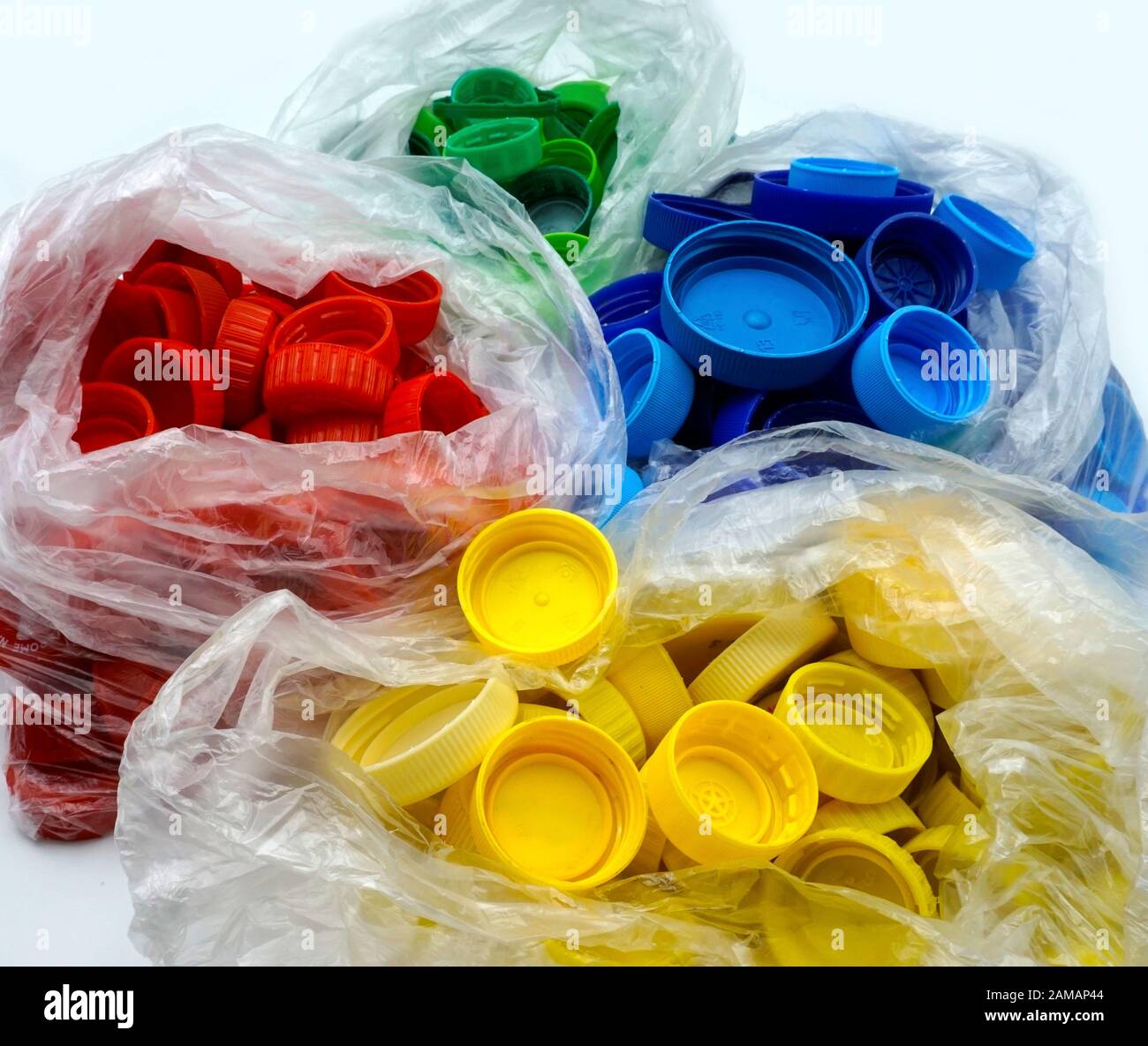 Bunte Kunststoff-Flaschenverschlüsse nach Farben sortiert in transparenten Einmalbeuteln aus Kunststoff. PP eine PET-Verschmutzung. Recycling-Lösungen für Kunststoffabfälle. Oben Stockfoto