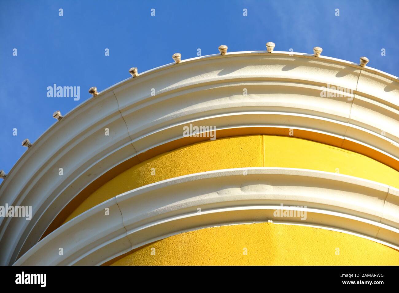 Ein Detail eines hellen und sonnigen gelben Gebäudes gegen einen klaren blauen Himmel Stockfoto