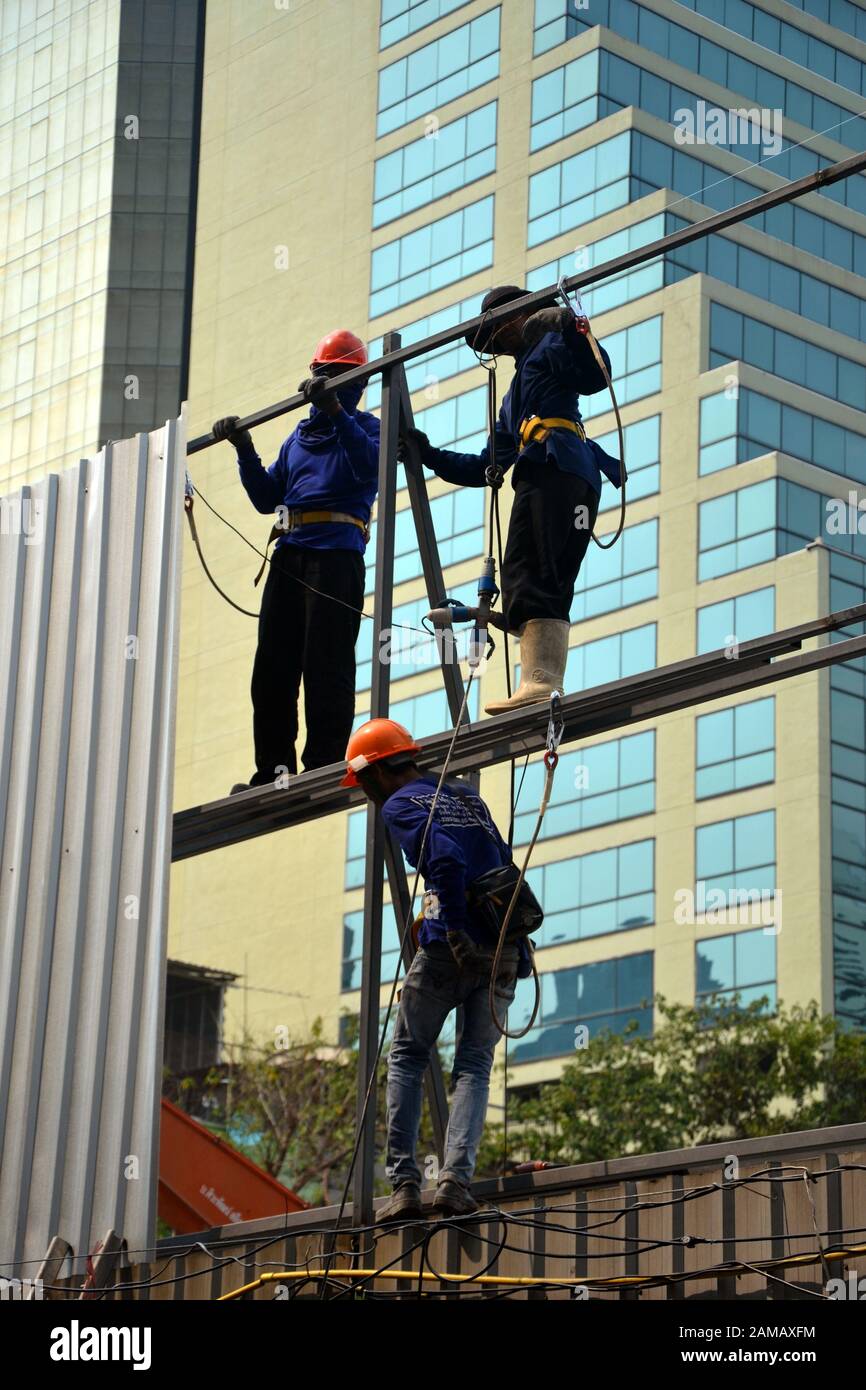 Drei Arbeiter, die an einem Zaun auf einer Baustelle in Bangkok, Thailand, Asien arbeiten Stockfoto