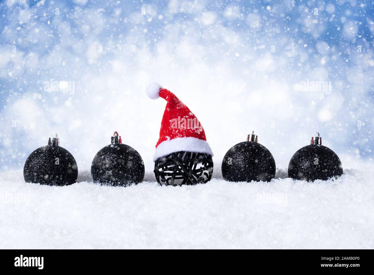 Blauer Weihnachtshintergrund - Dekorierte schwarze Kugeln mit Santa hat On Snow mit Schneeflocken und Sternen. Stockfoto