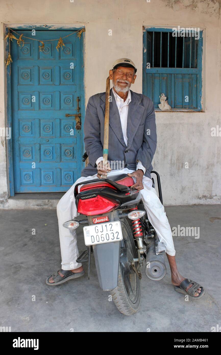 Älterer Mann der Rabari Tribe sitzt auf einem Honda-Motorrad Maringana Village, Gujarat, Indien Stockfoto