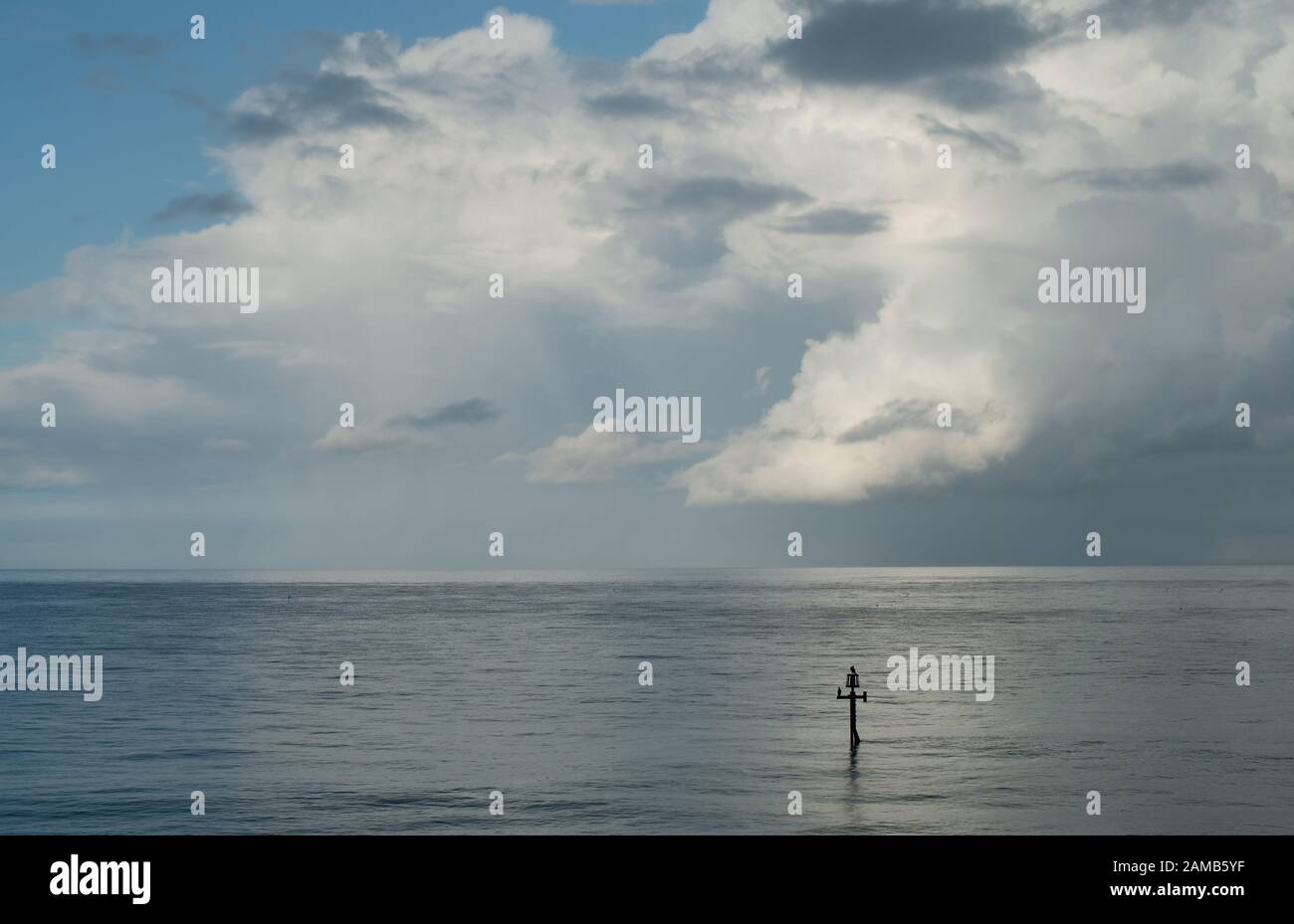 Eine klassische minimalistische Szene aus Meer, Horizont-blauem Himmel und sanft beweglichen Wolken ohne Ablenkungen, die in wunderschönem Licht gefangen sind Stockfoto