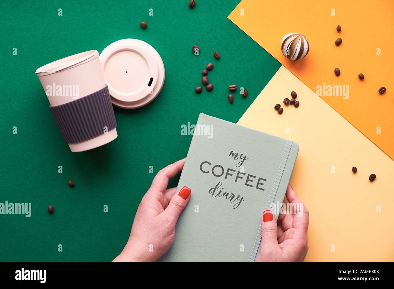 Null-Abfall-Kaffeekonzept. Umweltfreundliche wiederverwendbare Kaffeetassen in Händen, geometrische Draufsicht auf geteiltem Papier in Grün-, Gelb- und Orangenfarben, Text Stockfoto