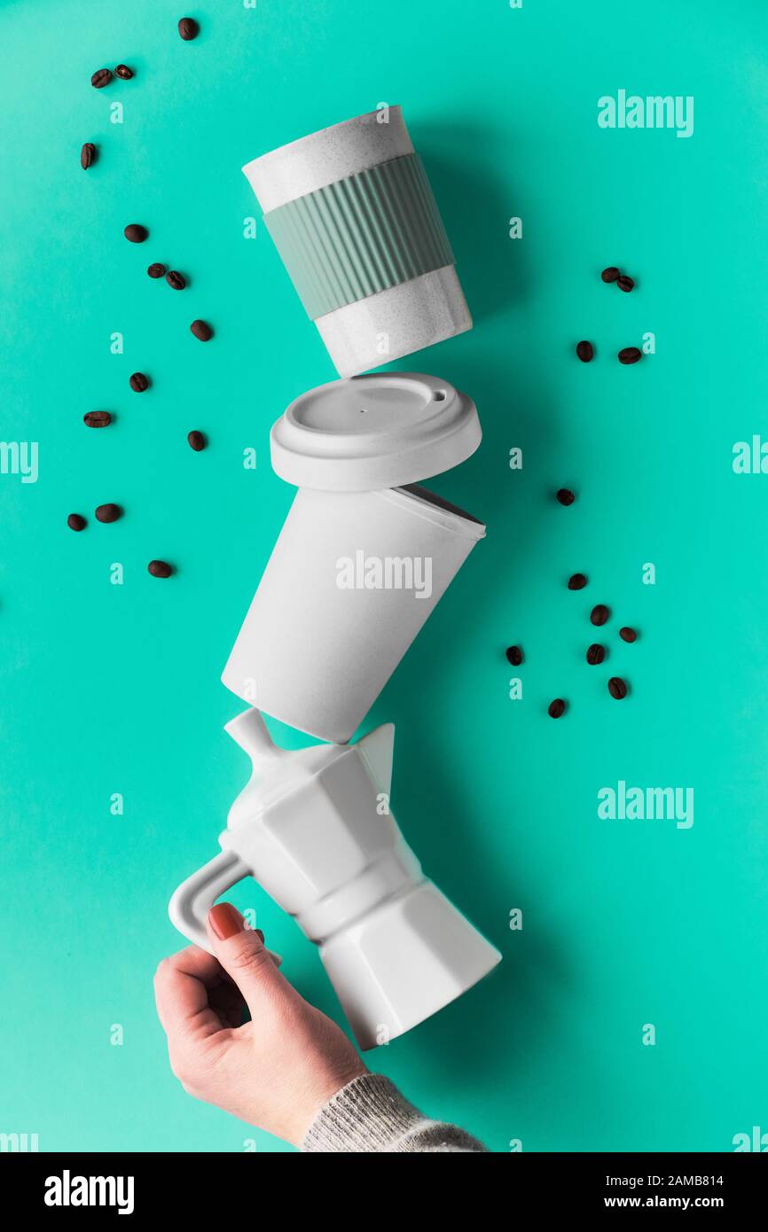 Balancierung der Kaffeepyramide ohne Abfall in weiblichen Händen auf grünem Minzhintergrund. Espresso-Kaffeemaschine aus Keramik und umweltfreundlicher wiederverwendbarer Bambuskaffee mu Stockfoto