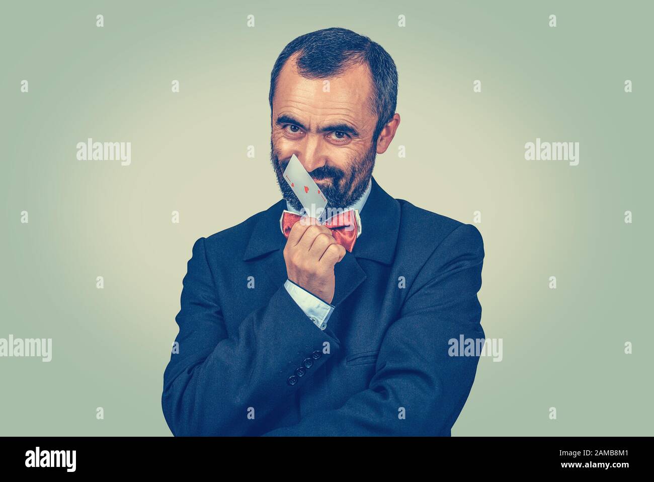 Bärtiger Geschäftsmann lächelt kratzend und berührt seine Nase mit einem Ass Karte Lügner, phonischer Mann, Thump-Konzept. Gesichtsausdrücke des Menschen. Isolierter Mann Stockfoto