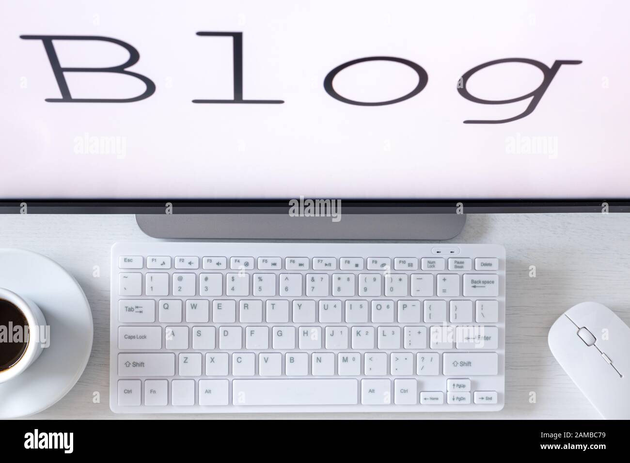 Text auf dem Monitor, Blog. Ein Schreibtisch mit Computertastatur und eine Tasse Kaffee. Das Konzept, Ihre eigene Website für das Internet zu betreiben Stockfoto