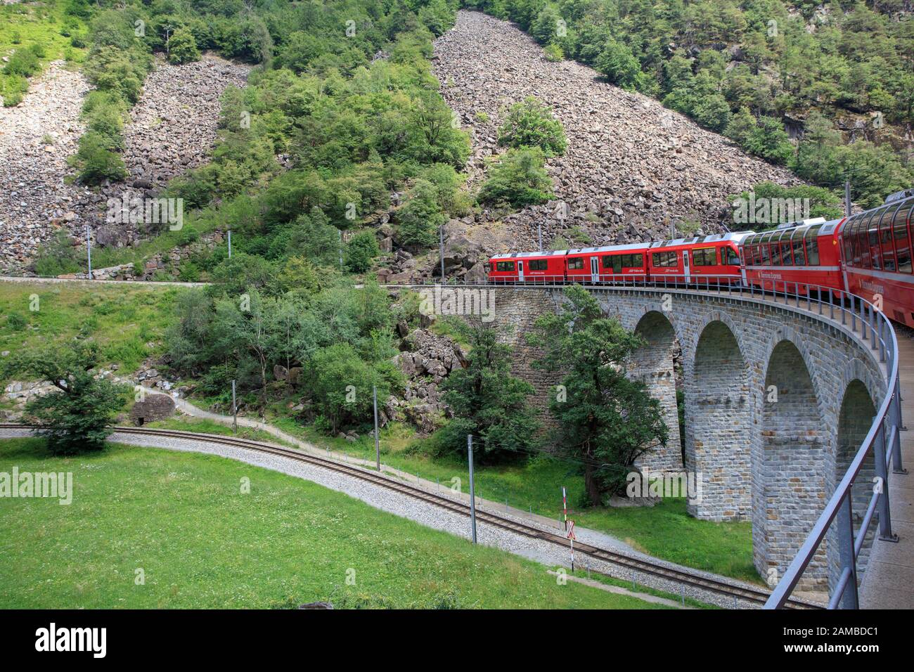 Bernina-Express-Zug, der durch das Spiralviadukt Brusio, Graubunden, Schweiz, führt Stockfoto