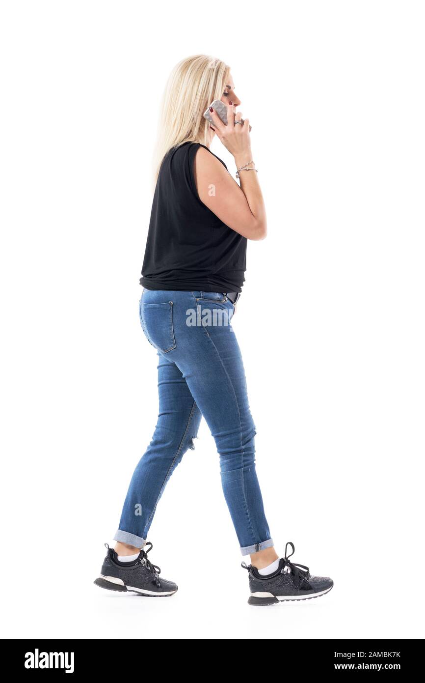 Seitenansicht einer Frau im mittleren Alter, die mit viel Stress unterwegs ist und eilig mit dem Handy spricht. Volle Körperlänge auf weißem Hintergrund isoliert. Stockfoto