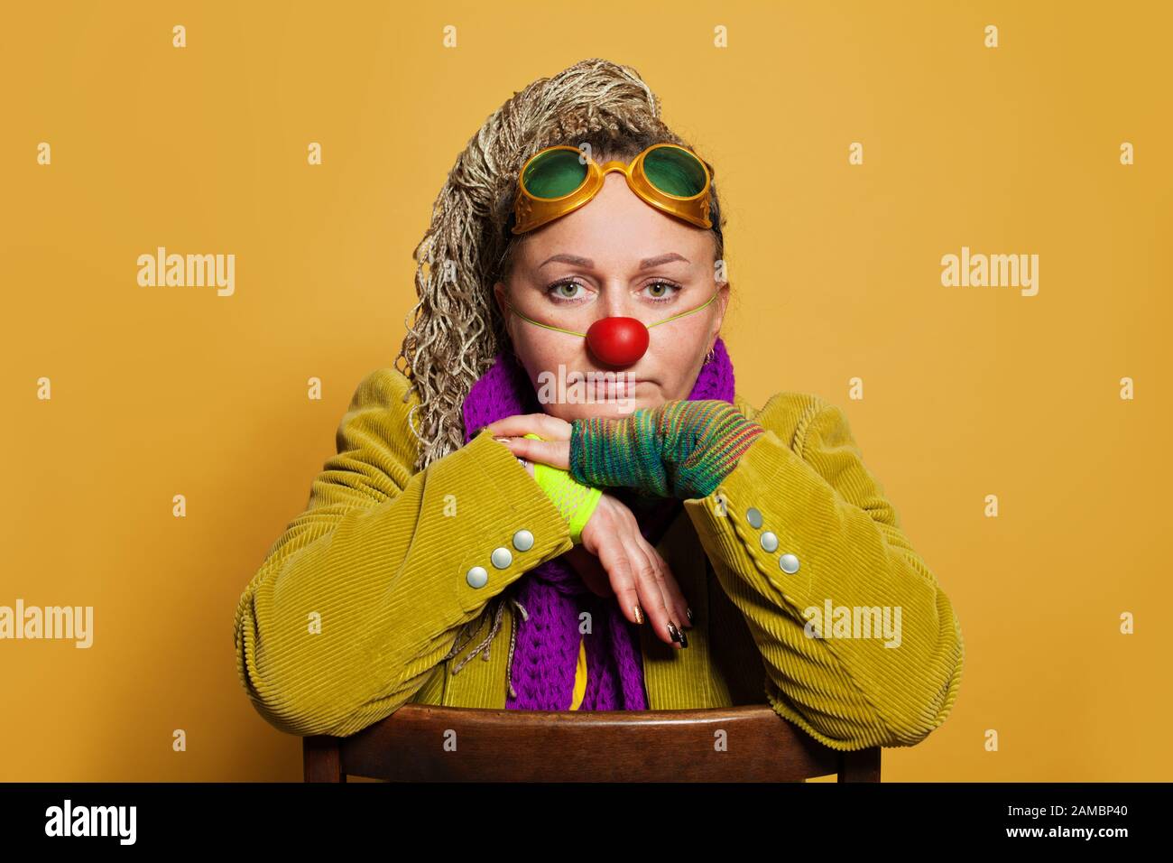 Reife Frau Psychologin im Clownkostüm zur Aufführung im Kinderhospiz auf gelbem Hintergrund. Echte Menschen Portrait Stockfoto