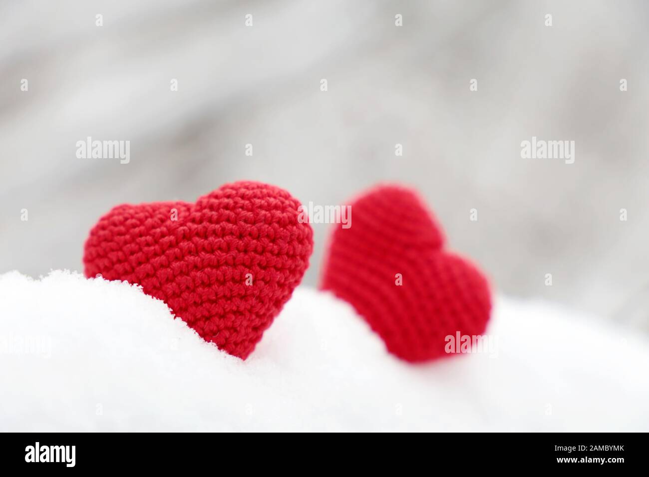 Liebesherzen, Valentinskarte, zwei rote Stricksymbole der Leidenschaft im Schneewald. Hintergrund für romantische Veranstaltungen, Feiern oder Winterwetter Stockfoto