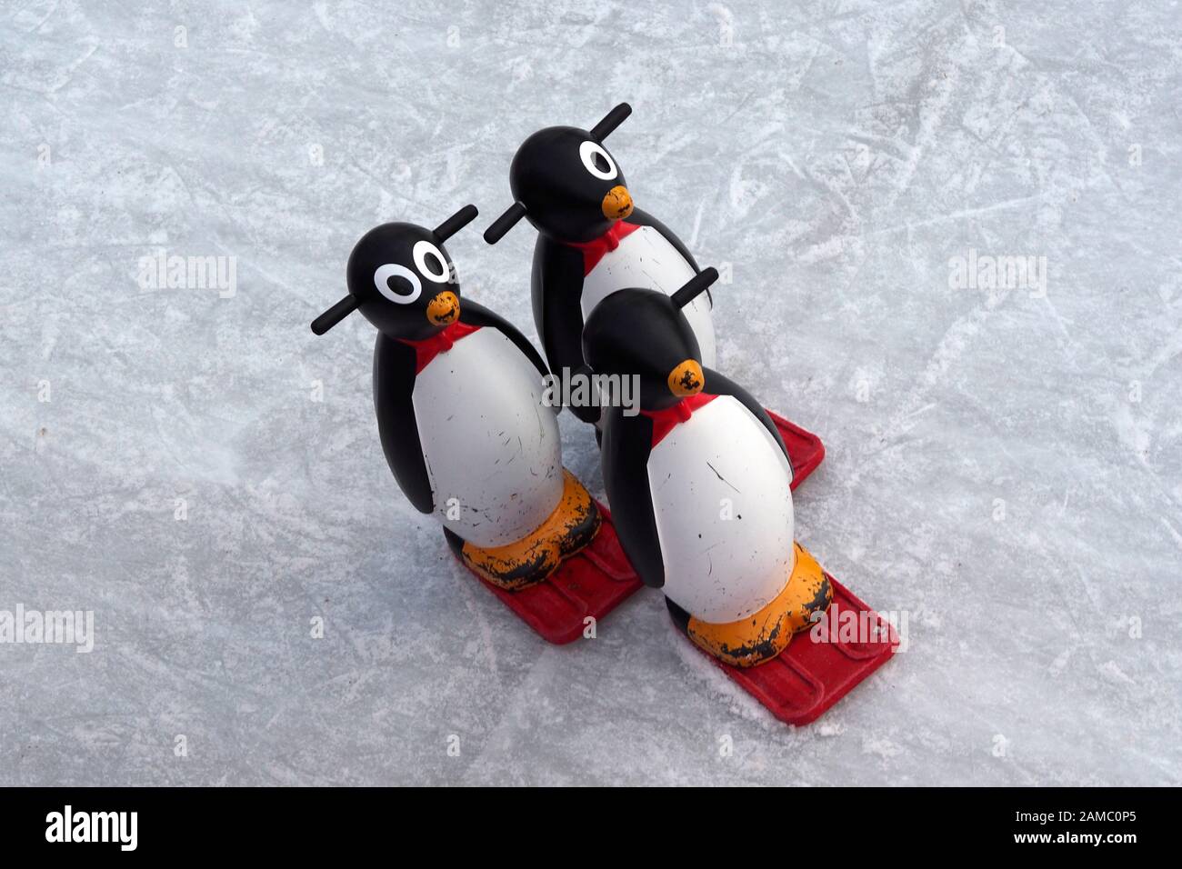 3 Pinguinhilfen auf einer Eisbahn sitzen Stockfoto