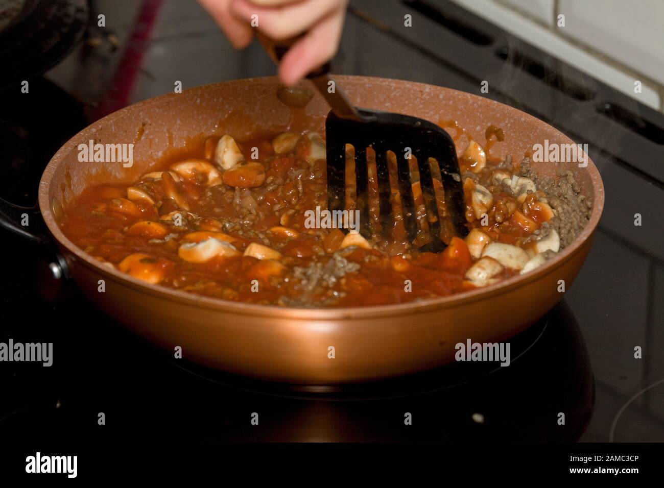 Rühren in Bolognesauce mit gemahlenem Hackfleisch und Champignons Stockfoto