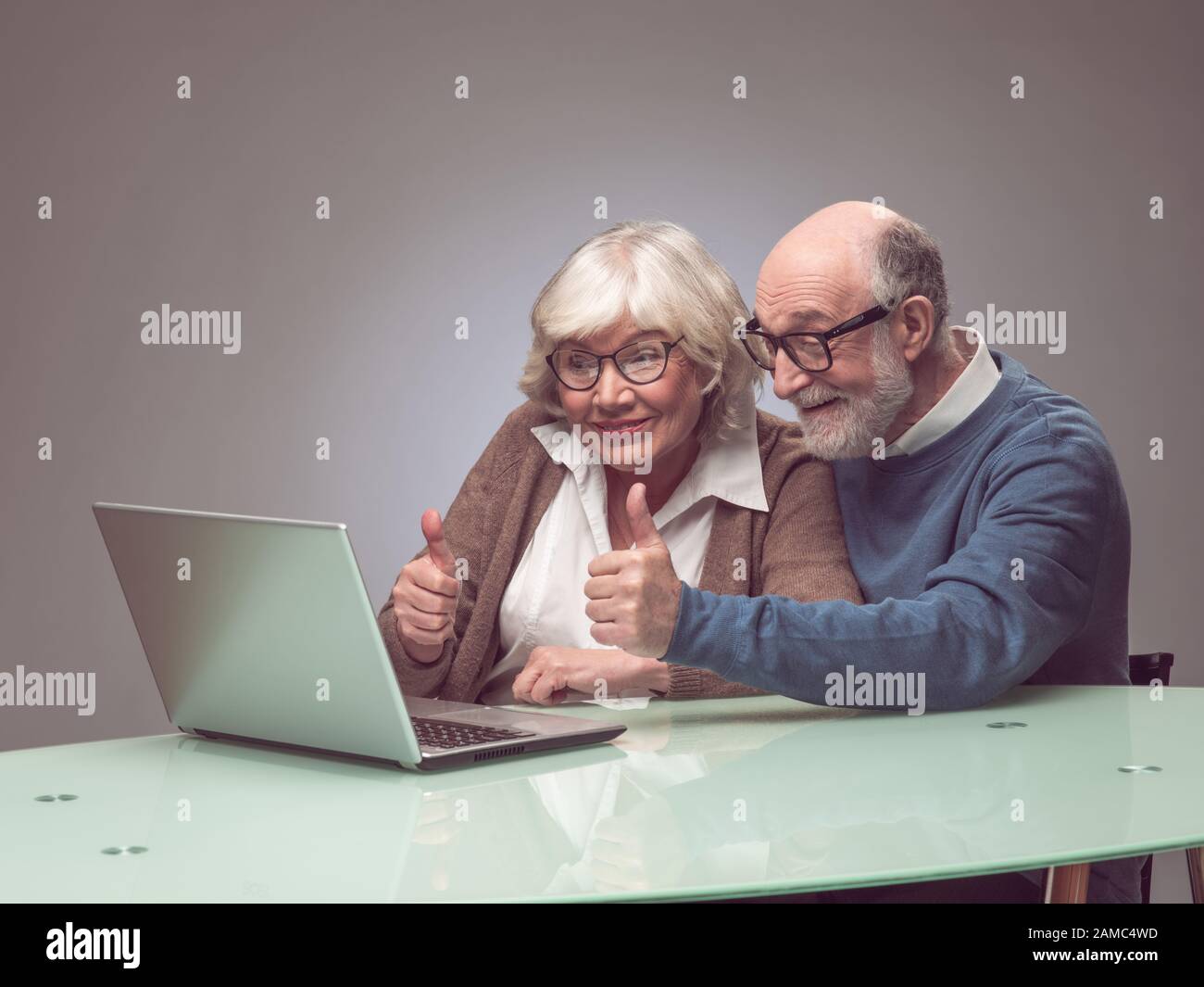 Älteres Paar, das Laptop zusammen verwendet und lächelt Stockfoto