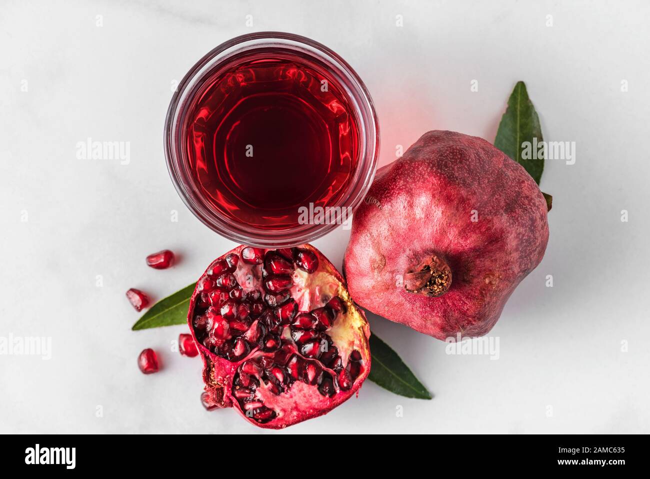 Glas Granatapfelsaft mit frischen Granatapfeln auf Marmortisch. Draufsicht. Konzept für gesunde Getränke Stockfoto