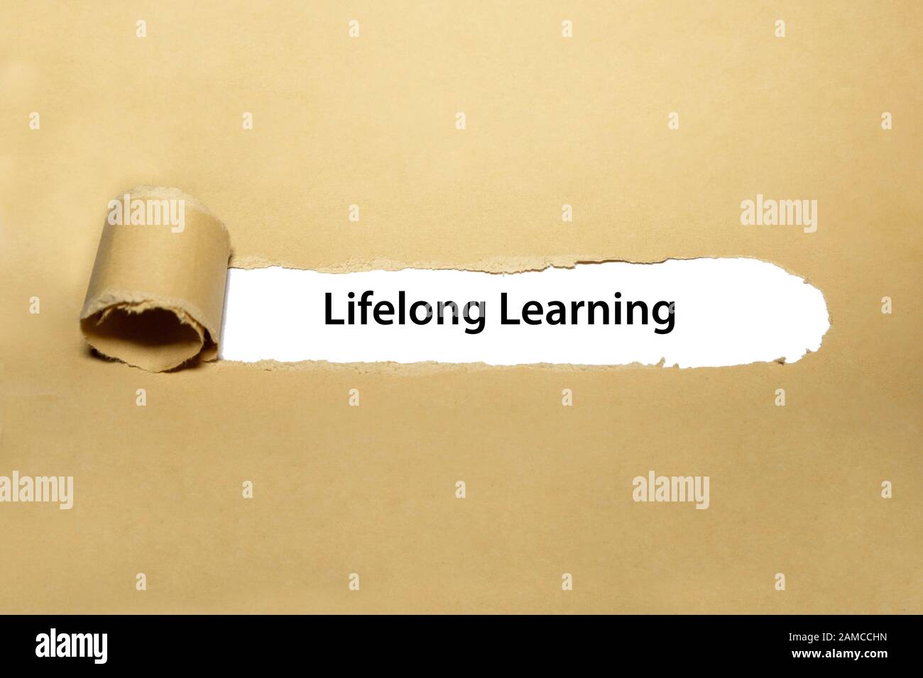Gedruckter Text Lebenslanges Lernen hinter geripptem braunem Papier. Selbstinitiiertes Bildungs- und Persönlichkeitsentwicklungskonzept. Stockfoto