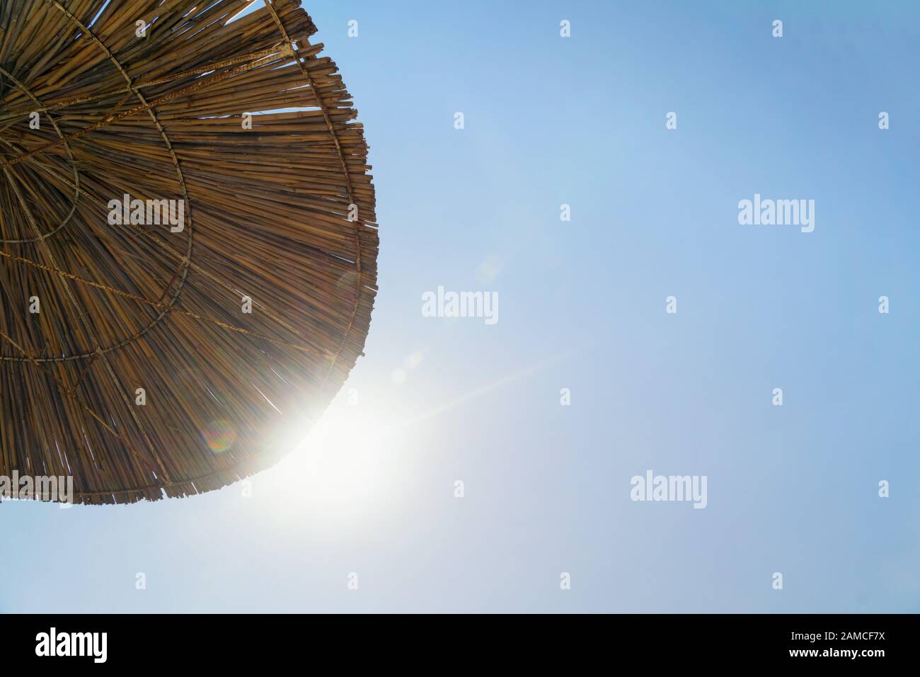 Sonnenschirm gegen blauen Himmel und Sonnenlicht. Sommerferienkonzept mit Kopierraum. Stockfoto