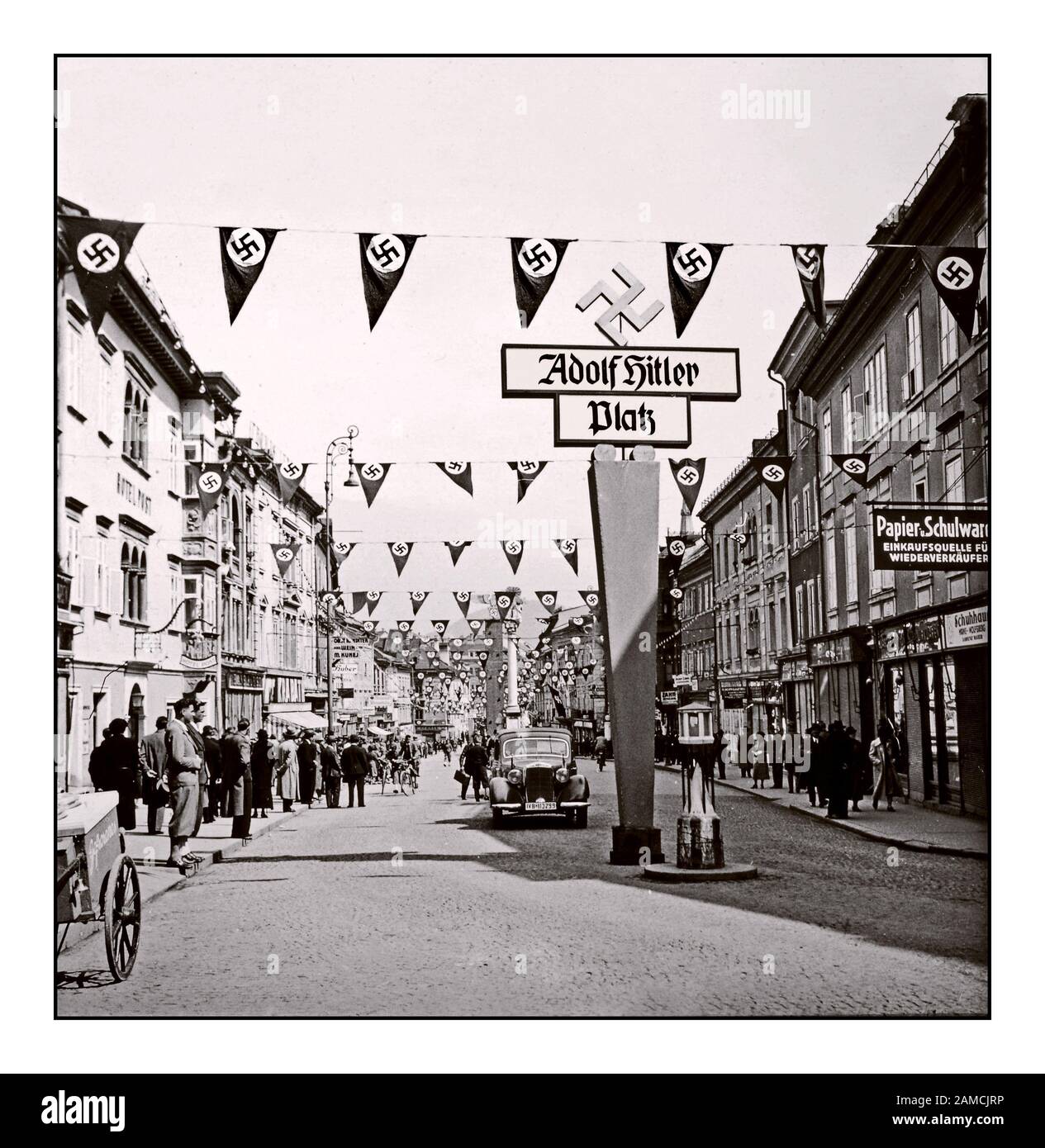 Jahrgang 1938 Osterreichische Annektierung Anschluss 5.03.1938 - Adolf Hitlers Kundgebung in Wien für die "Absorption Österreichs" in das Nazideutschland Dritte Reich. Flaggen und Banner mit dem Straßenschild „Adolf Hitler Platz“ feiern Österreichs aktive und freundliche Beteiligung an der Annexion des Adolf Hitlers Nazi Dritten Reiches 1938 Stockfoto