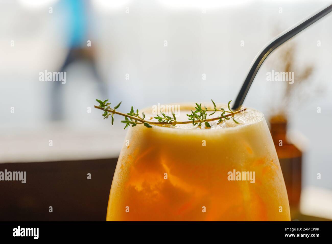 Nahansicht oben auf einem Glas kaltem Zitroneneis-Tee mit Strohhalm und Perücke über schaumigem und unscharfem Hintergrund der Straße im Freien. Stockfoto