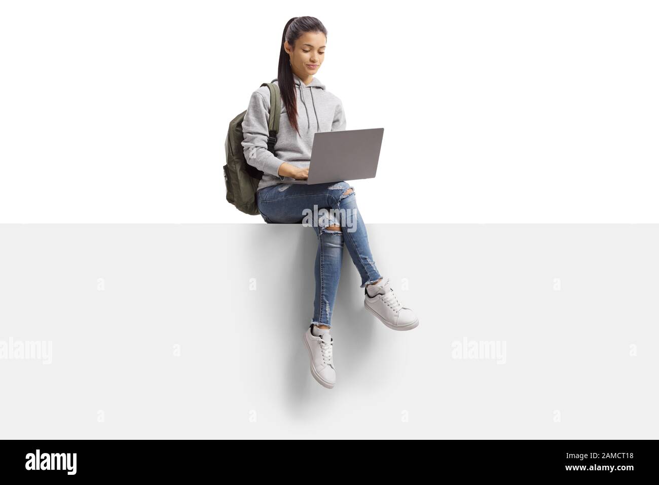 Studentinnen, die auf einem leeren Brett sitzen und einen Laptop verwenden, der auf weißem Hintergrund isoliert ist Stockfoto