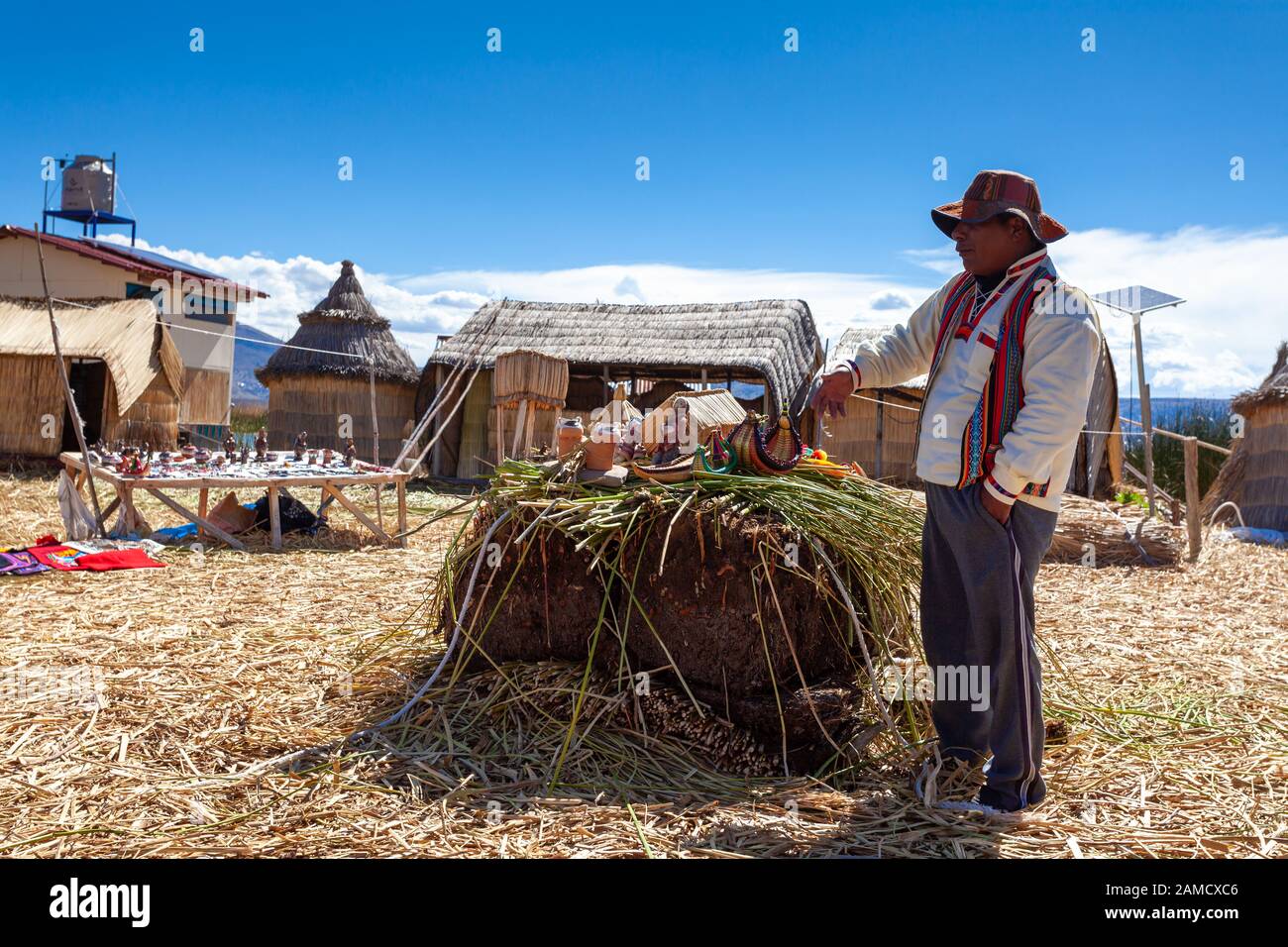 Schwimmende Inseln von Uros am Titicacasee in Peru, Südamerika - 2019-12-01. Ein Mann in einem Nationaltracht zeigt seine Produkte Stockfoto