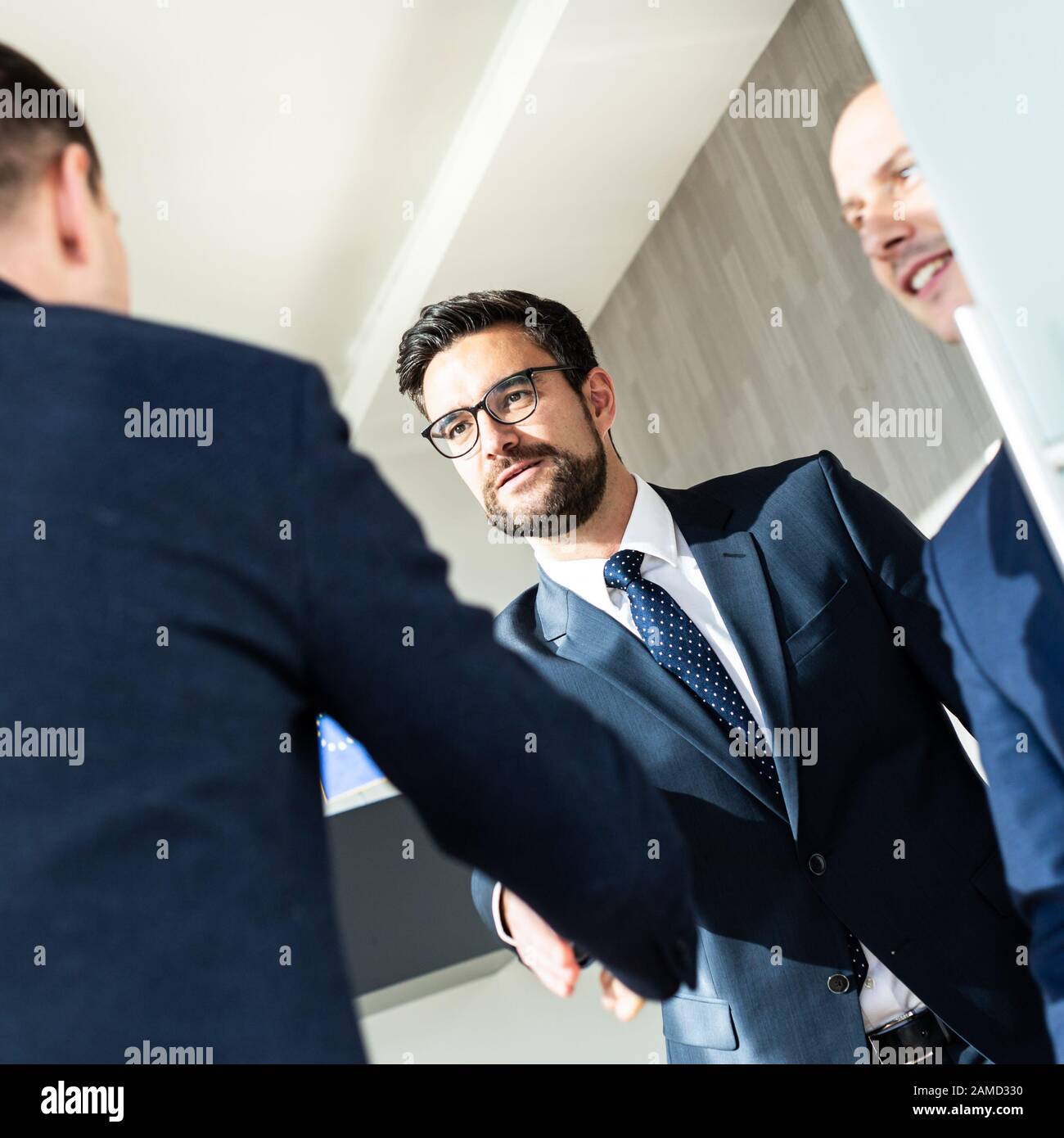 Eine Gruppe selbstbewusster Geschäftsleute grüßt bei Geschäftstreffen in modernen Büros mit einem Handschlag oder schließt die Vereinbarung, indem sie die Hände schütteln. Stockfoto