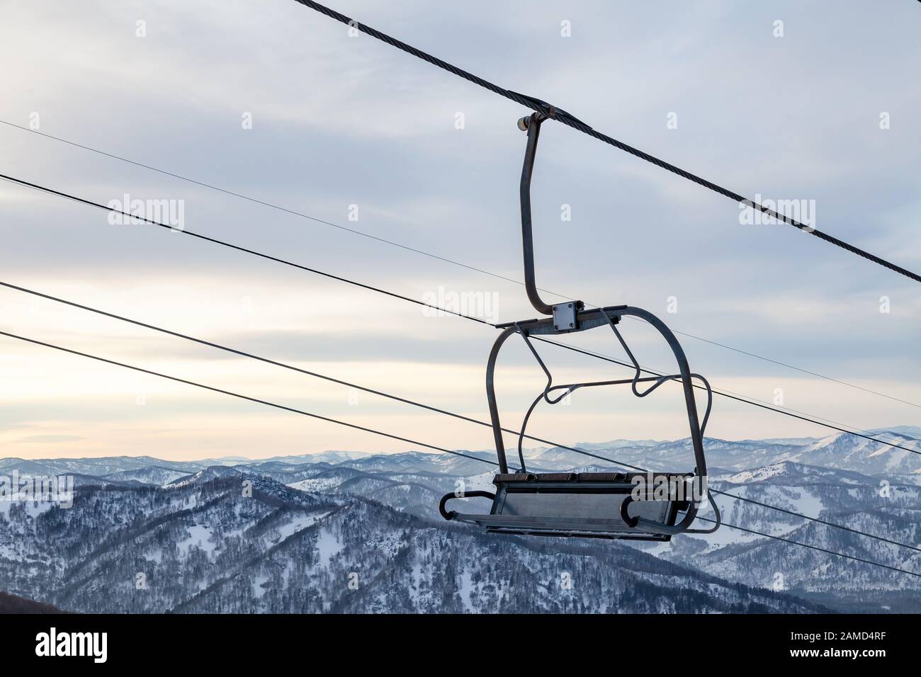 Eine Skilift-Sessellbahn mit einer Kabine, die an einem Kabel aufgehängt ist, in der Menschen mit Skiern und Snowboards auf einem Hintergrund von Bergen sitzen, Bäume mit Sno Stockfoto
