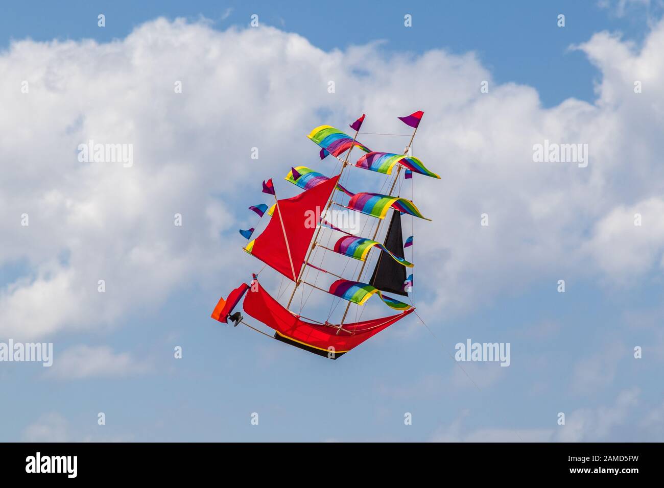 Rainbow Coloured Kite in Form eines hohen Schiffes am Himmel, Bali, Indonesien. Stockfoto